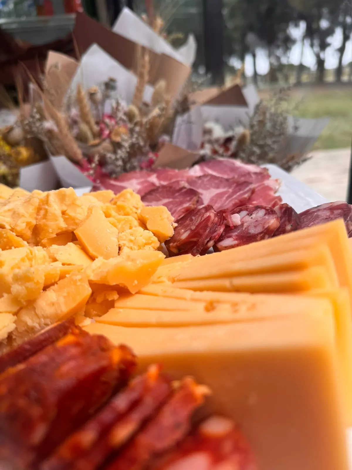 Detalle real de picada con queso, chacinados y flores secas